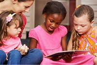 Imagen de niñas leyendo con su maestra.