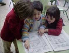 Imagen de tres niños en la escuela mirando un periódico